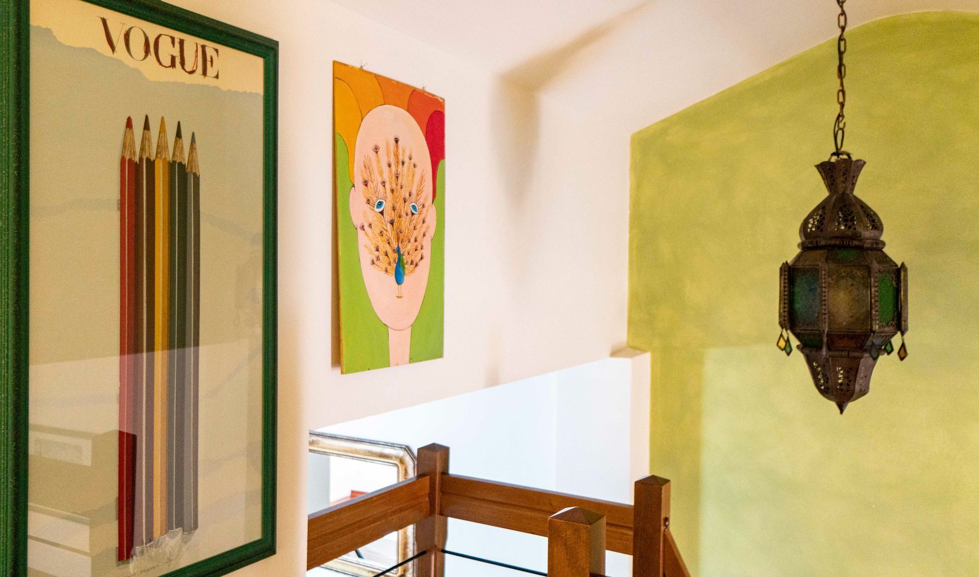 A room with a framed magazine cover, a colorful artwork, and a hanging lantern.
