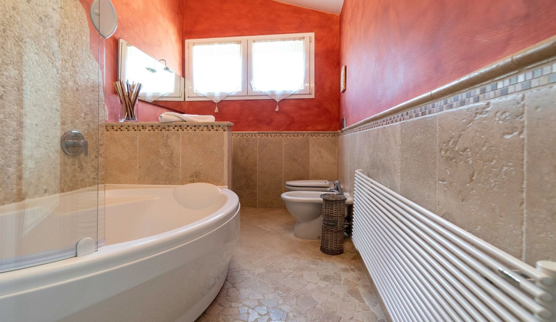 A bathroom with a freestanding bathtub, a toilet, and a window.