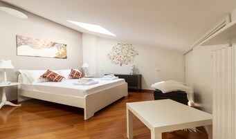 A bedroom with a bed, bedside tables, a desk, and a decorative wall piece.