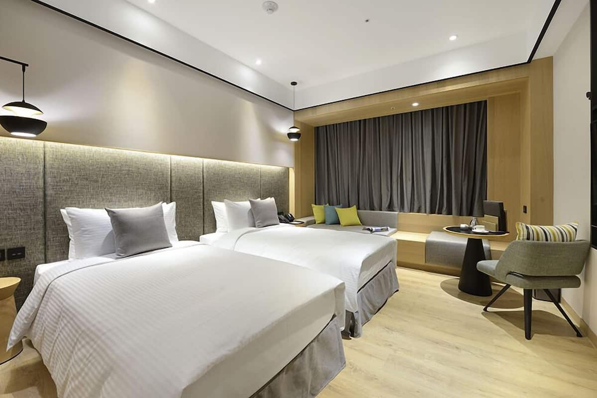 Una habitación de hotel moderna con dos camas, un sofá, una silla y una pequeña mesa.