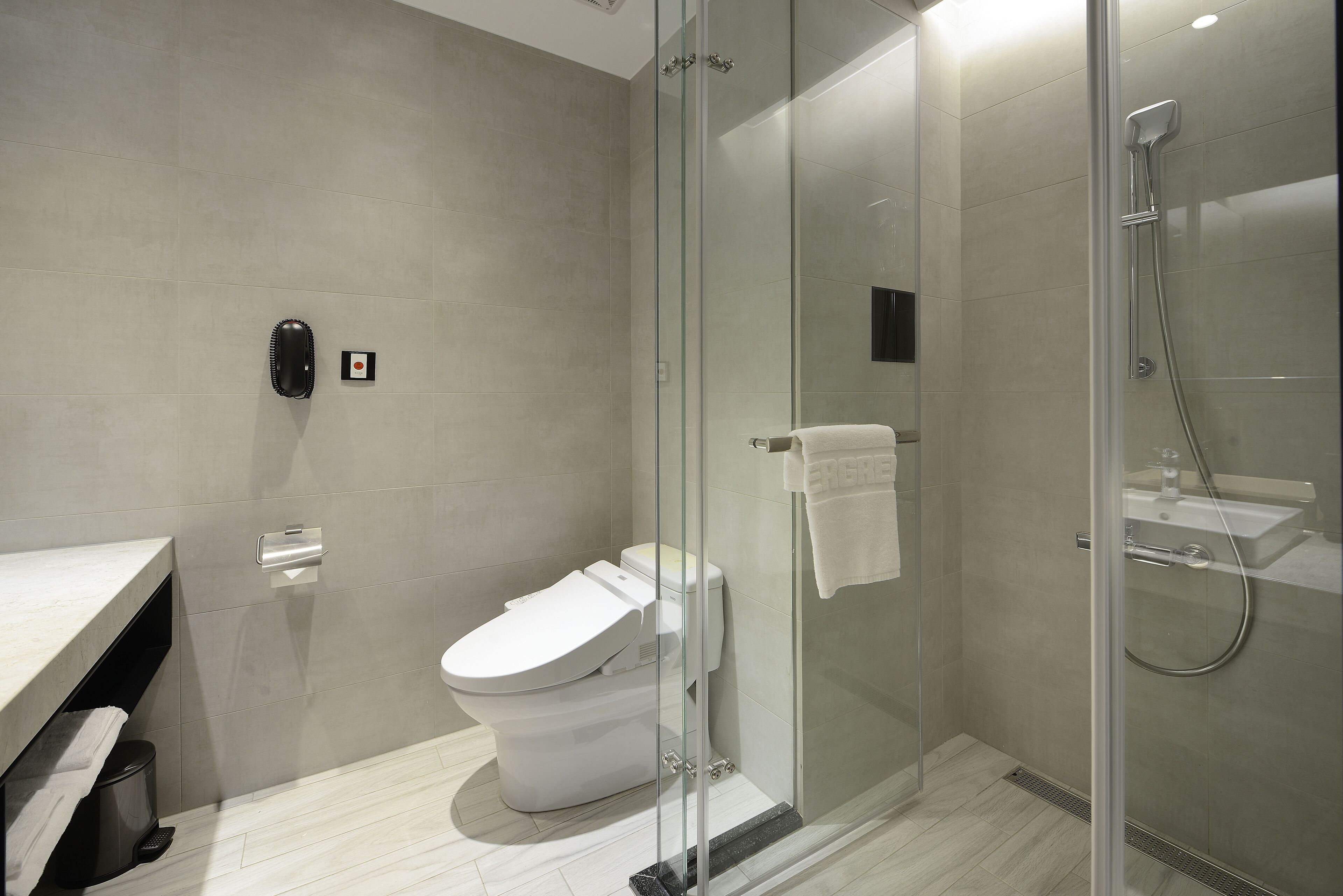 A modern bathroom with a toilet, glass shower enclosure, and a sink.
