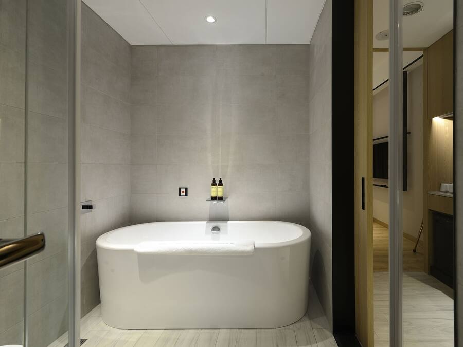 A modern bathroom with a large freestanding bathtub, a glass shower enclosure, and a wooden vanity with a mirror.