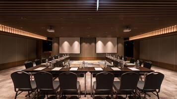 A conference room with a long table, chairs, and a projector screen.