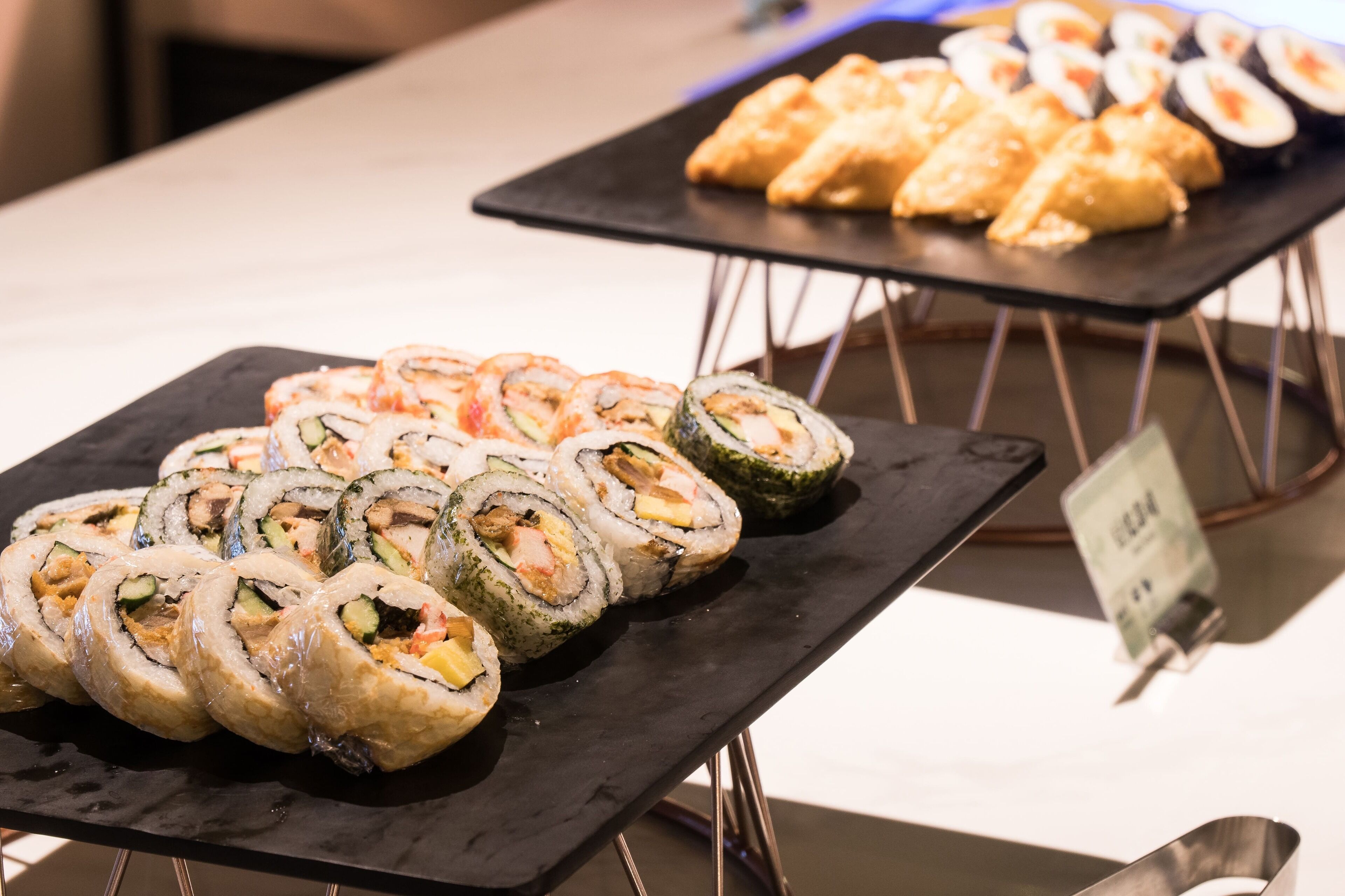 Presentación de sushi con diferentes tipos de sushi sobre bandejas negras.