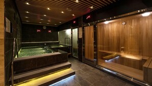 Un spa moderno con un amplio jacuzzi, sauna y baño de vapor.