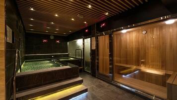 Relax in a serene hot tub with a glass enclosure, adjacent to a sauna with glass doors.