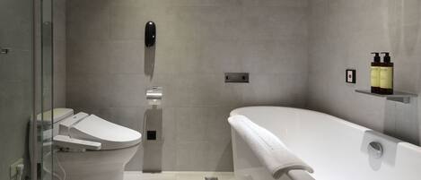 A modern bathroom with a toilet, bidet, and bathtub.