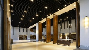 Un vestíbulo espacioso con techo alto, grandes columnas de madera y una zona de estar central.