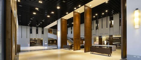 Un vestíbulo espacioso con techo alto, grandes columnas de madera y una zona de estar central.