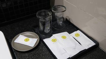 Una bandeja con dos vasos, un plato con servilleta, y dos servilletas blancas con un logotipo sobre una encimera.
