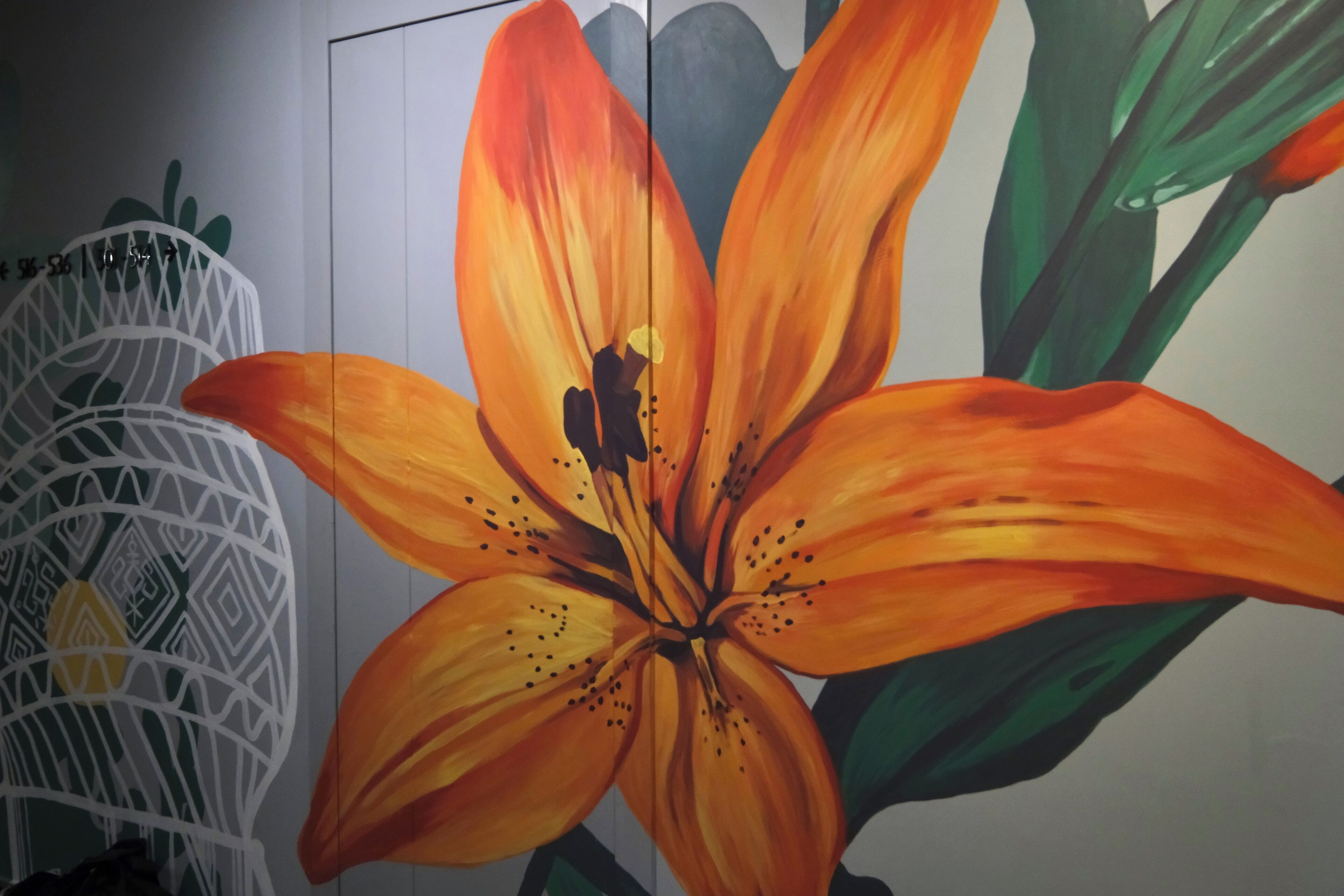 A large, vibrant orange flower mural on a wall.
