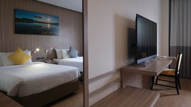 Una habitación de hotel con dos camas, un televisor de pantalla plana, un escritorio y una silla.