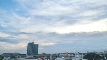 A cityscape with a prominent high-rise building, various smaller buildings, and a cloudy sky.