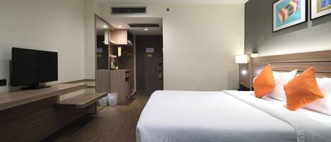 A hotel room with a bed, a television, a desk, and a bathroom visible through an open door.