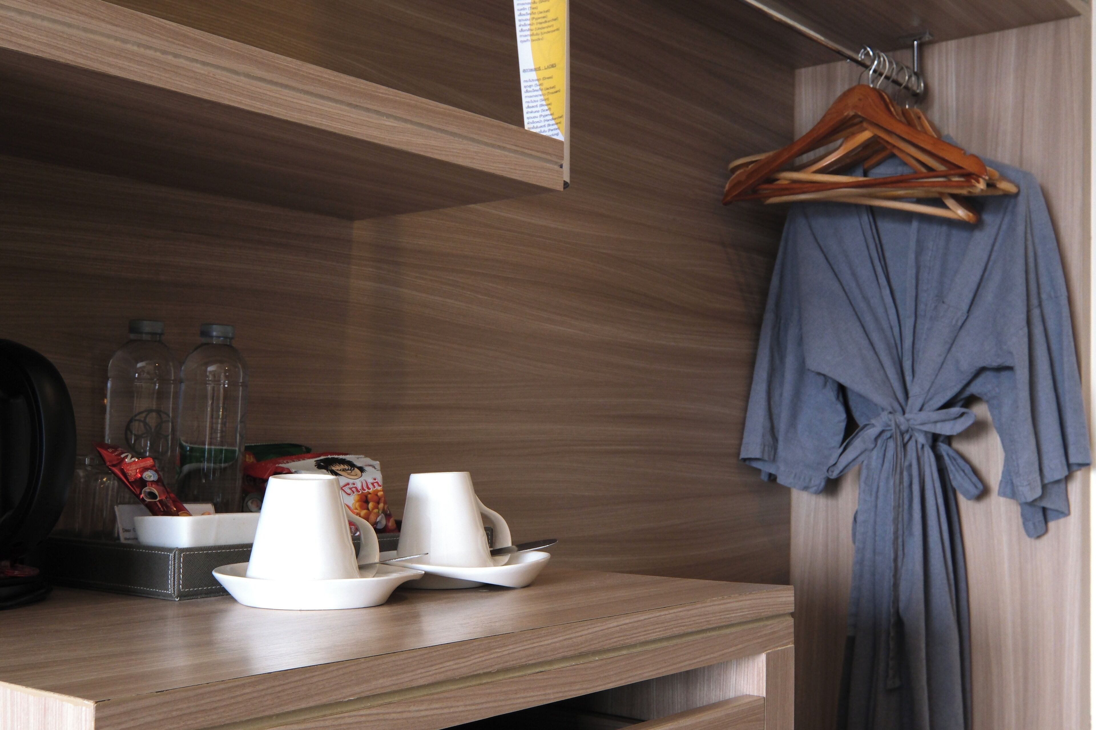 Une pièce bien rangée, avec une étagère en bois, un peignoir suspendu et un plateau contenant des tasses et un bol.