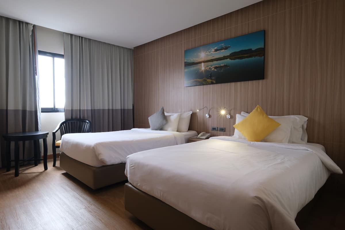 Ein Hotelzimmer mit zwei Betten, einem Schreibtisch und einem Gemälde an der Wand.