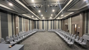 Un salón de conferencias con una larga mesa, filas de sillas y piso alfombrado.