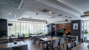 Un restaurante moderno con techos altos, ventanas amplias y diversas opciones de asientos.