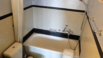 Un baño con bañera, ducha, inodoro y toallero.