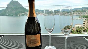 A bottle of Valdobbiadene Prosecco Superiore DOCG and two empty wine glasses on a table with a cityscape view.