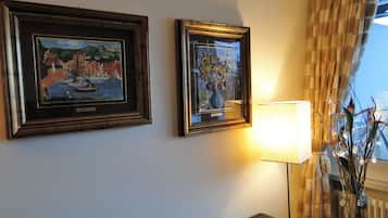 Two framed artworks on a wall, a lamp, and a window with curtains.