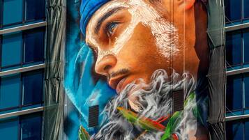 A building facade with a large mural of a person wearing a blue headscarf and a beard.
