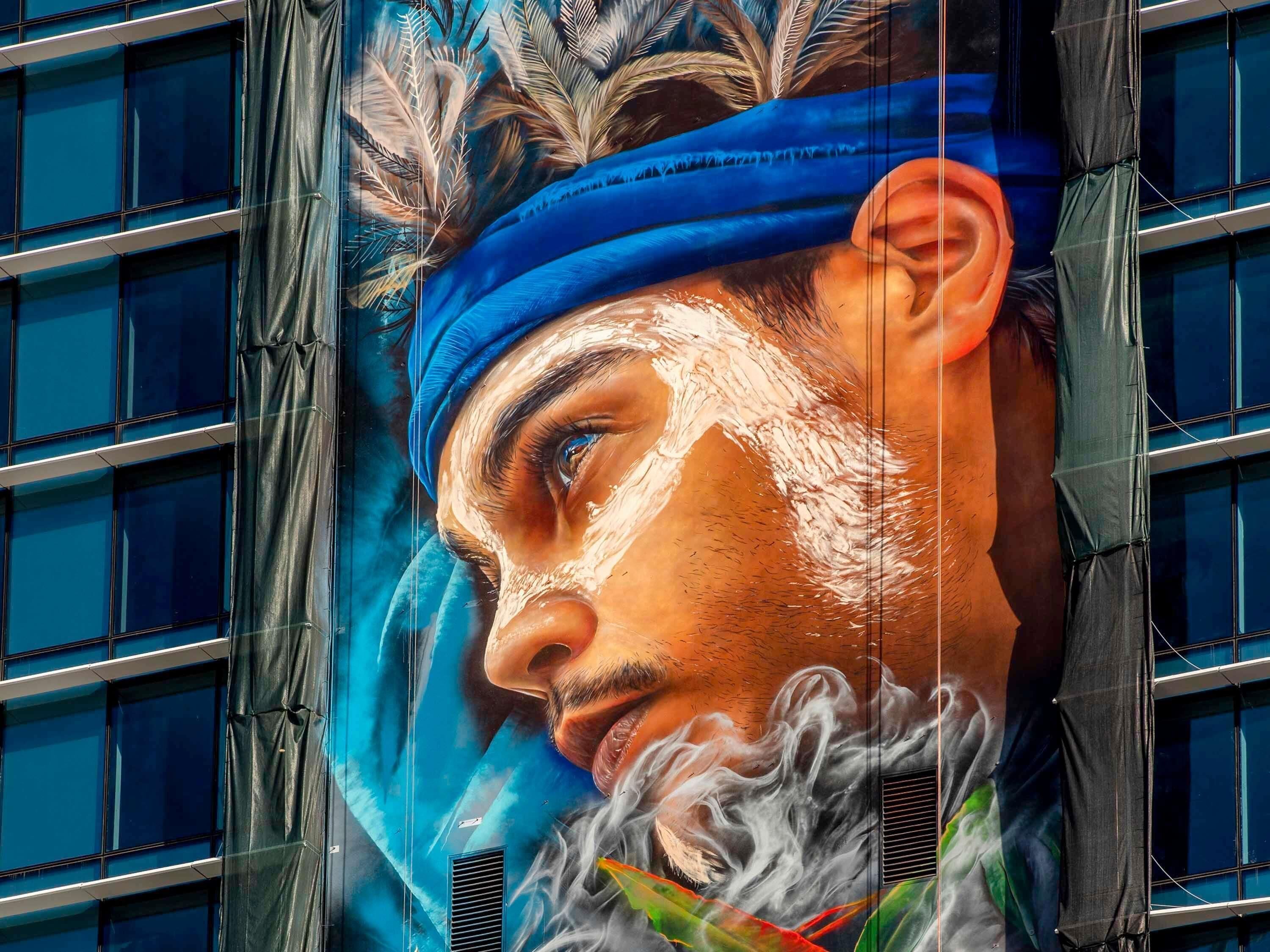Un mural de una persona con cinta azul en la cabeza y barba.