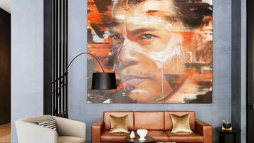 A modern living room with a large abstract painting, a leather sofa, a side table, and a floor lamp.