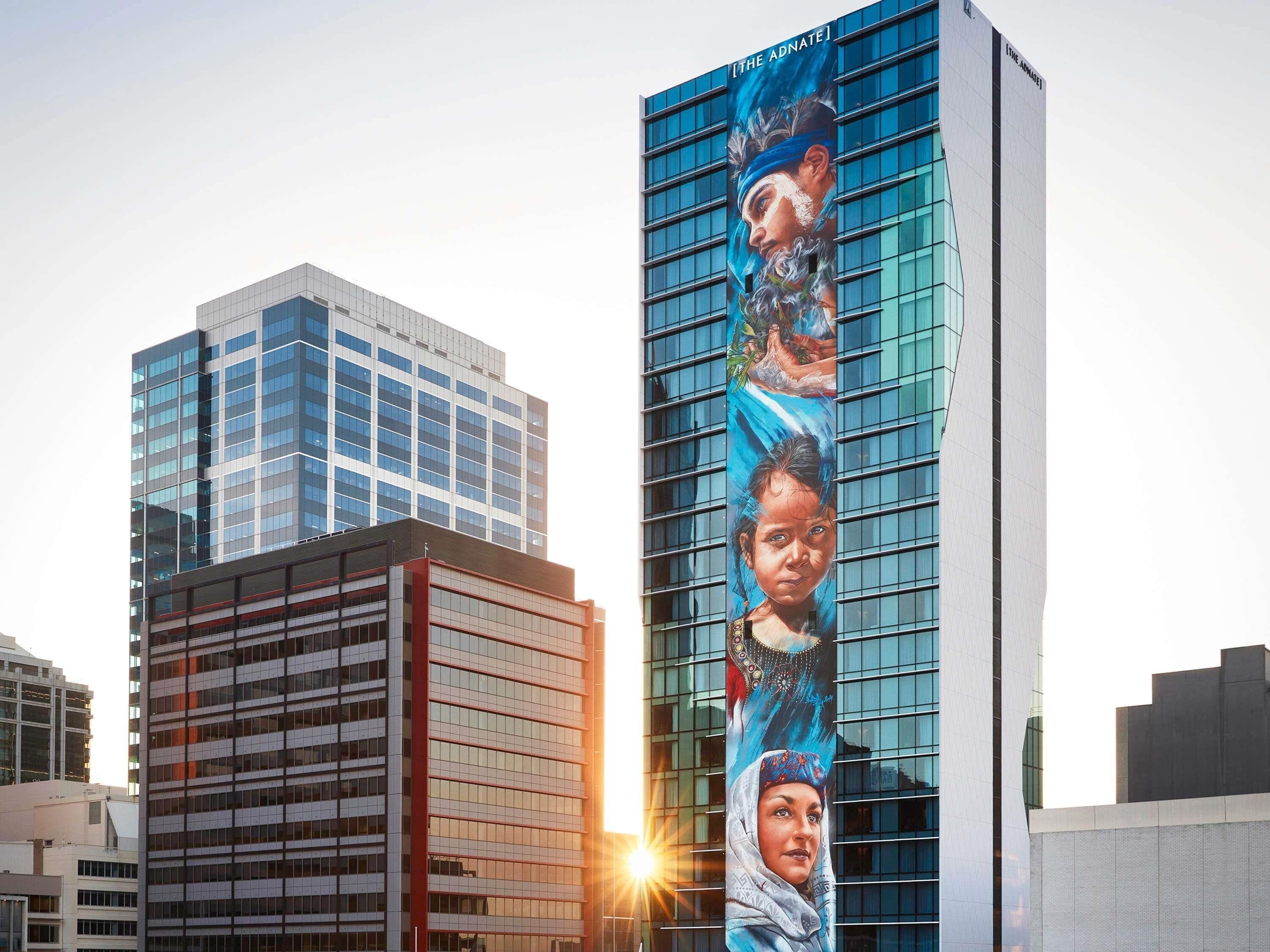A modern high-rise building with a large vertical advertisement featuring a person.