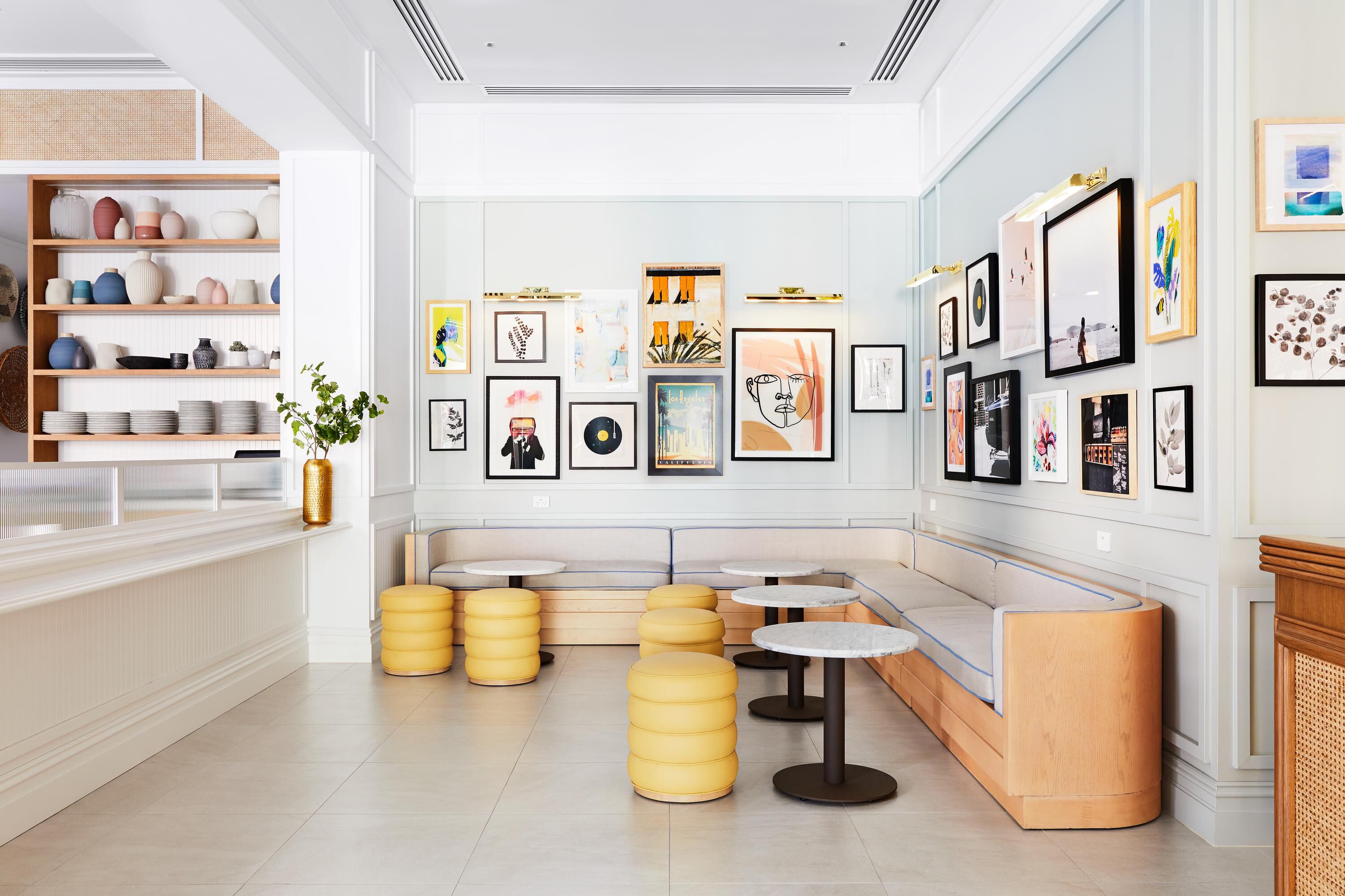 Un interior moderno con una zona de estar, estanterías con objetos decorativos y obras de arte enmarcadas en las paredes.