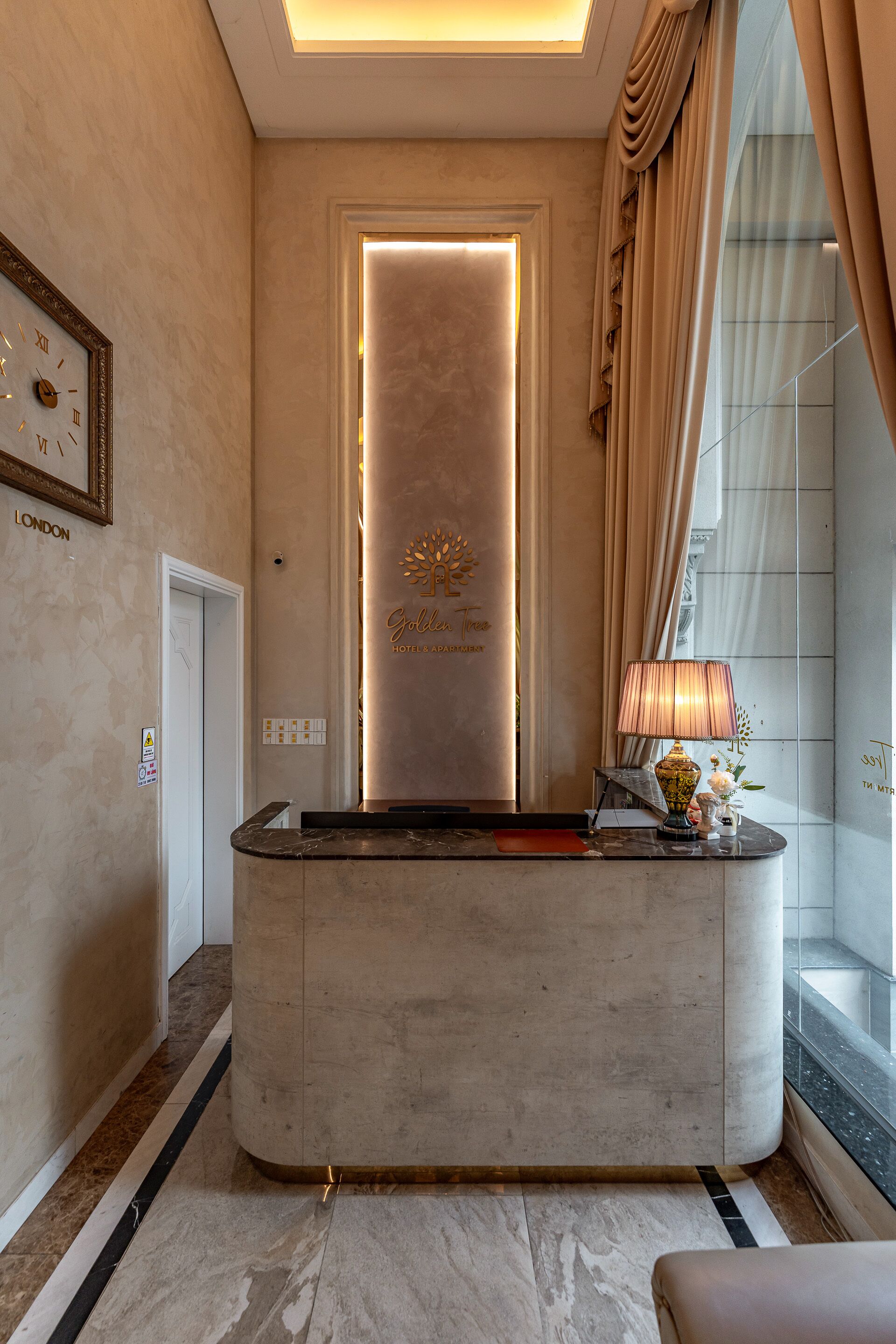 A hotel reception area with a marble counter, a framed clock, and a sign reading "Goldstone Hotels & Resorts".