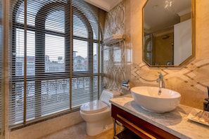 Ein modernes Badezimmer mit großem Fenster, Toilette, Waschbecken und Spiegel.