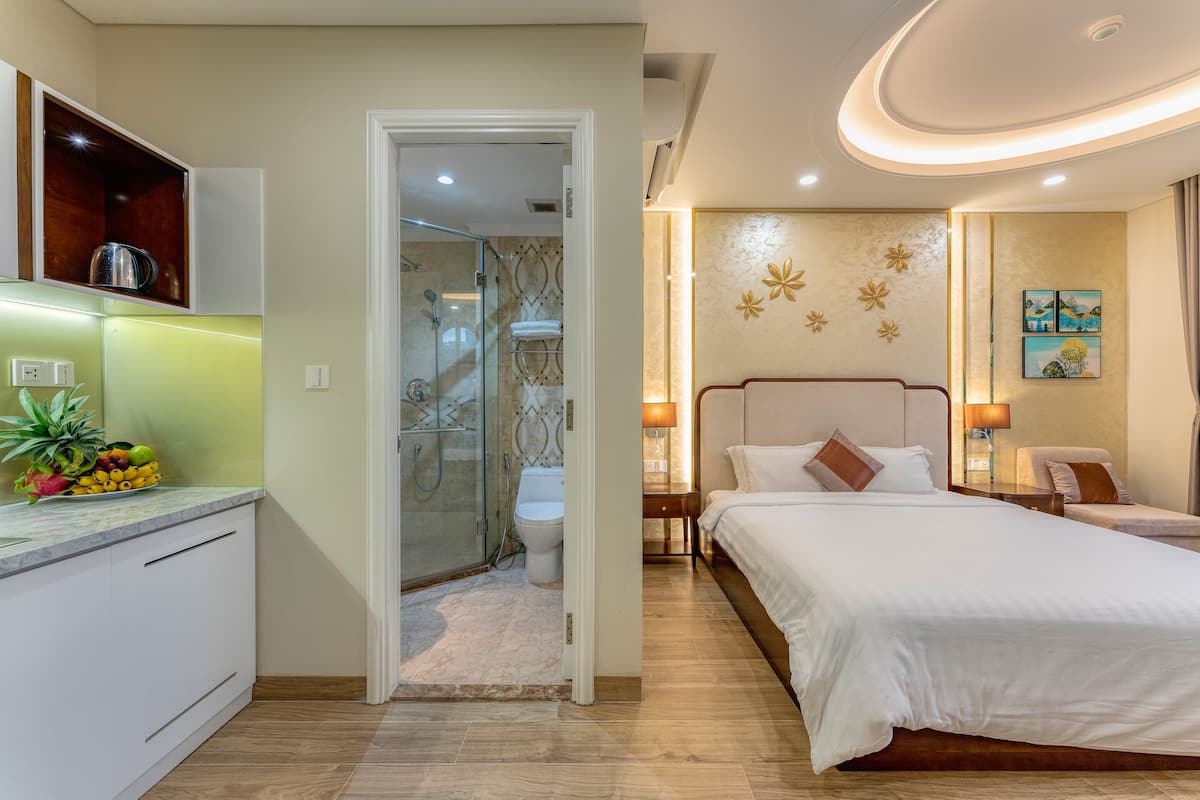 A modern hotel room with a large bed, a separate bathroom, and a small sitting area.