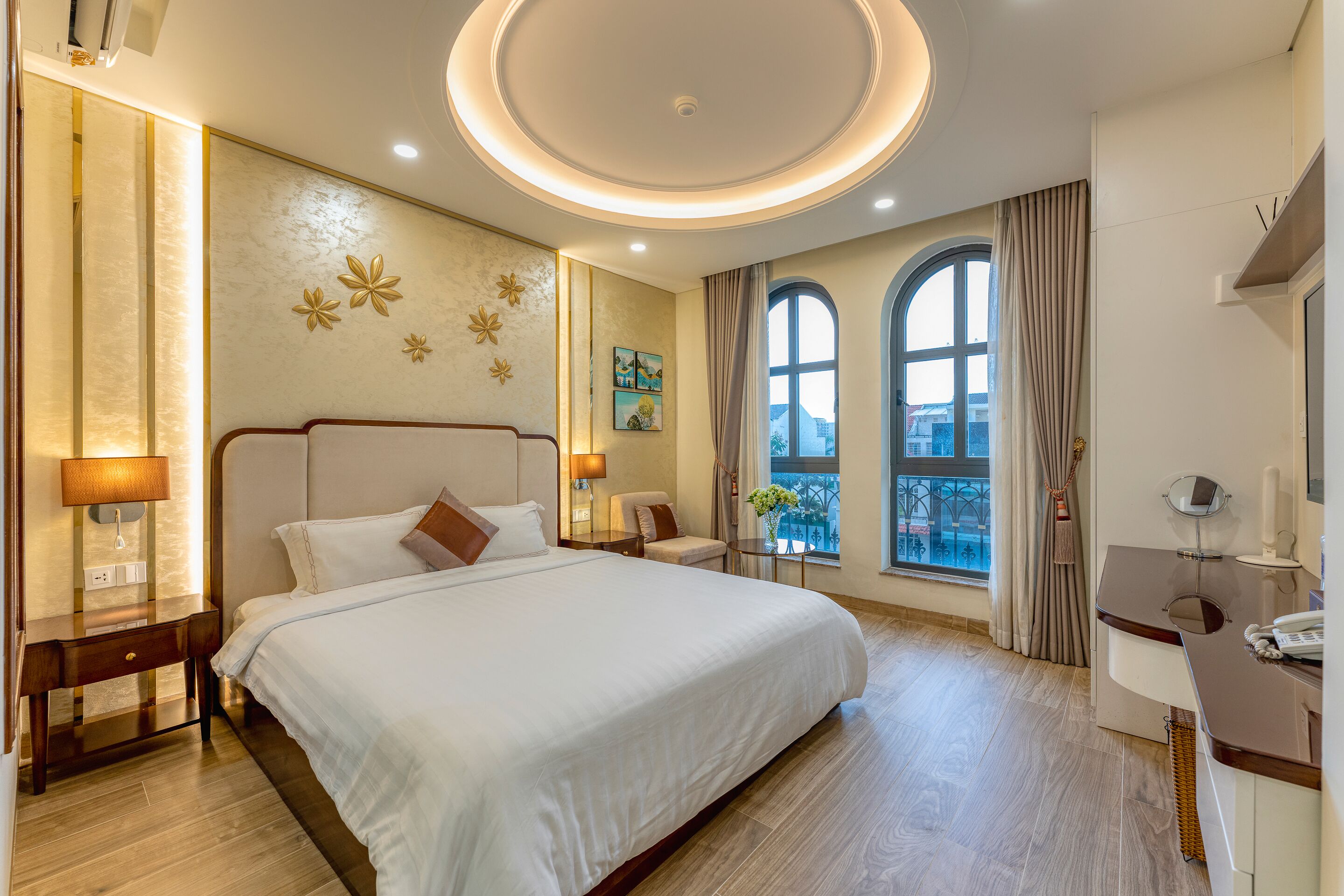 Une chambre d’hôtel avec un grand lit, des tables de chevet, un bureau et une fenêtre avec des rideaux.