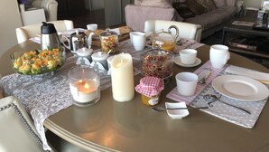 A dining table set with various items including a fruit bowl, candles, a teapot, and a jar of jam. - Les Grimaldines - Maison d'Hotes C 2 Bis (Cagnes-sur-Mer)