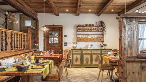 A rustic dining area with wooden furniture and a tiled floor. - Horse House (Novella)