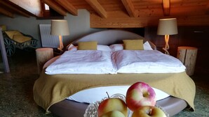 A bedroom with a bed, bedside lamps, a wooden ceiling, and a table with apples. - Horse House (Novella)