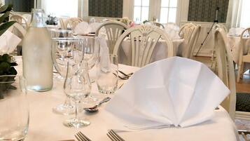 Mesa de jantar posta para uma recepção de casamento, com toalhas brancas, copos e cartão de menu.
