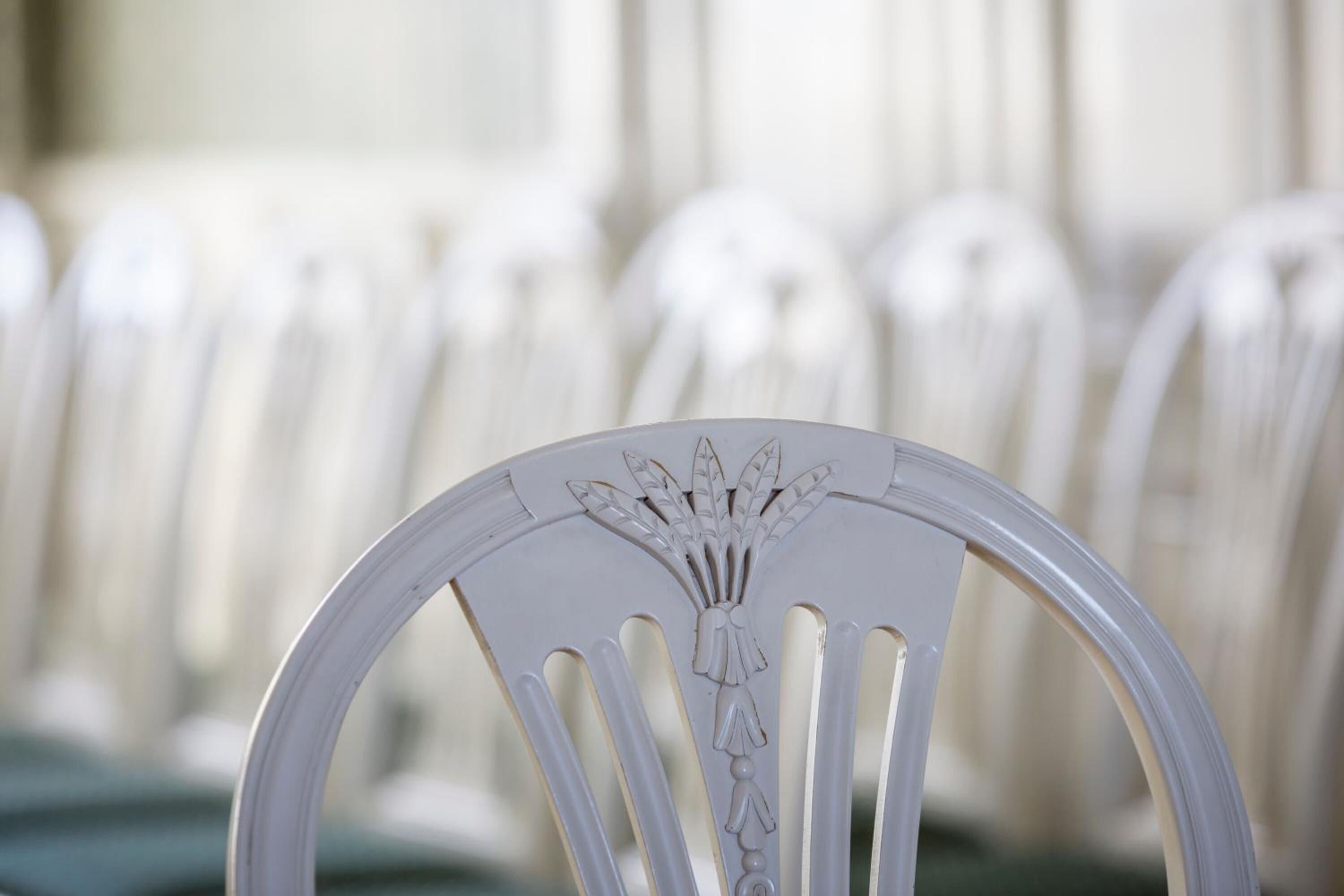 A row of white chairs with a decorative backrest design.
