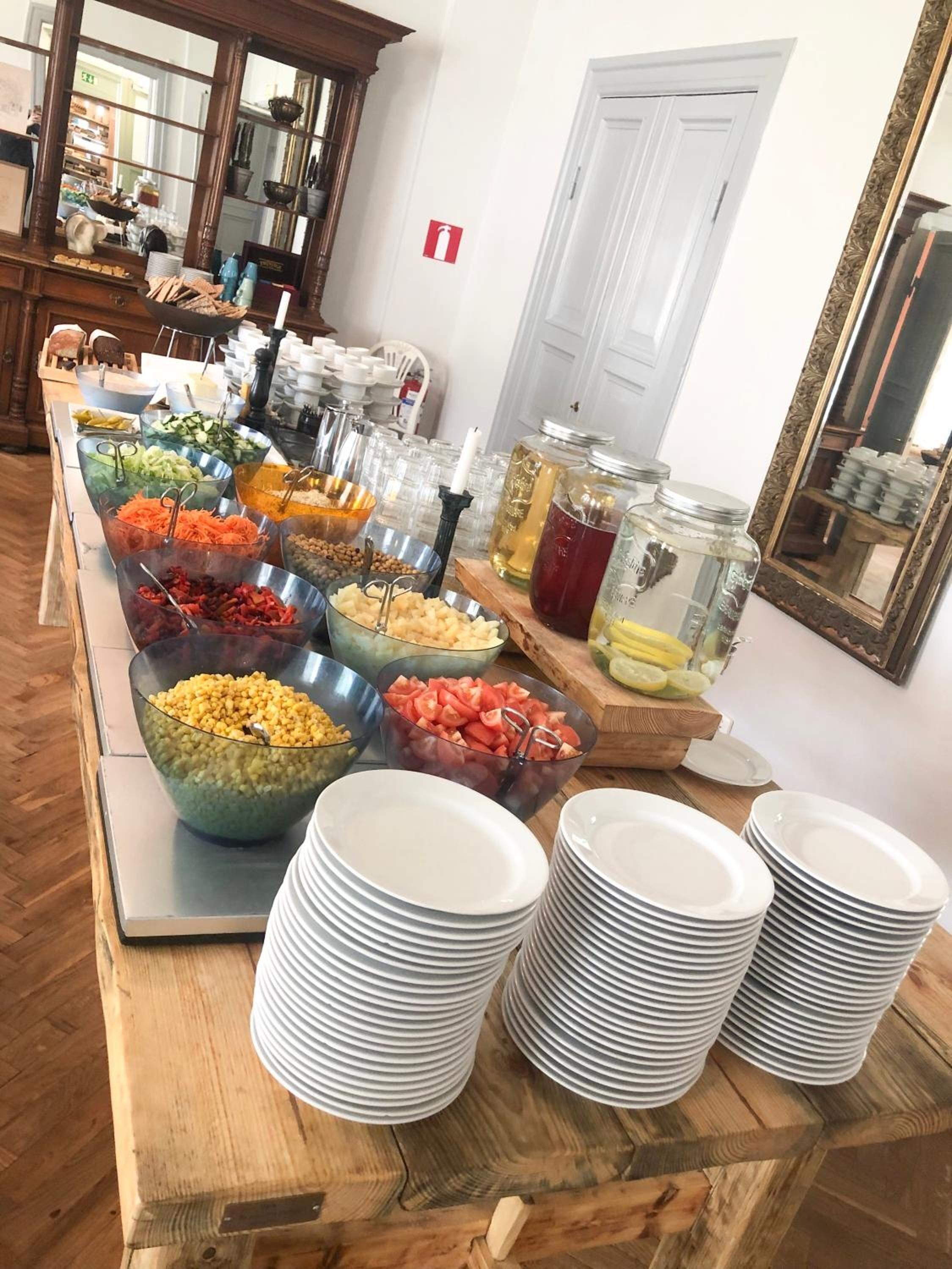 A buffet setup with various food items and stacked plates.