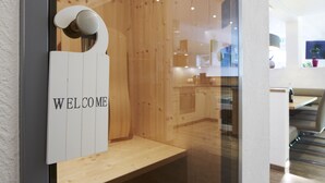 A wooden interior with a 'WELCOME' sign, a bench, and a glimpse of a dining area. - Apartment Goldeck (Ried im Oberinntal)