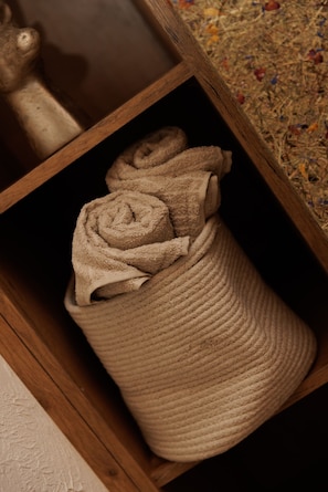 A wooden shelf with a woven basket containing rolled towels. - Apartment Goldeck (Ried im Oberinntal)
