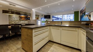 A modern kitchen with a wooden island, built-in appliances, and a large window offering a view of the city. - Apartment Goldeck (Ried im Oberinntal)