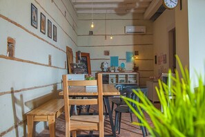 Relax in a cozy café with rustic charm, featuring a wooden bench and framed pictures, serving coffee.