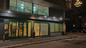 A modern hotel with a glass facade, green entrance doors, and a sign indicating a 4-star rating. - Crystal Hotel Varese (Varese)