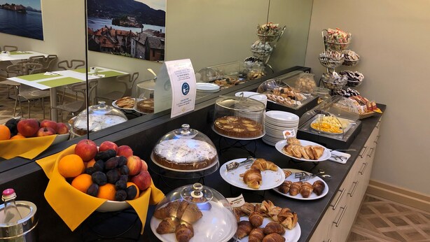 A buffet with various food items including fruits, pastries, and a cake. - Crystal Hotel Varese (Varese)