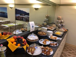 A buffet with various food items including fruits, pastries, and a cake. - Crystal Hotel Varese (Varese)