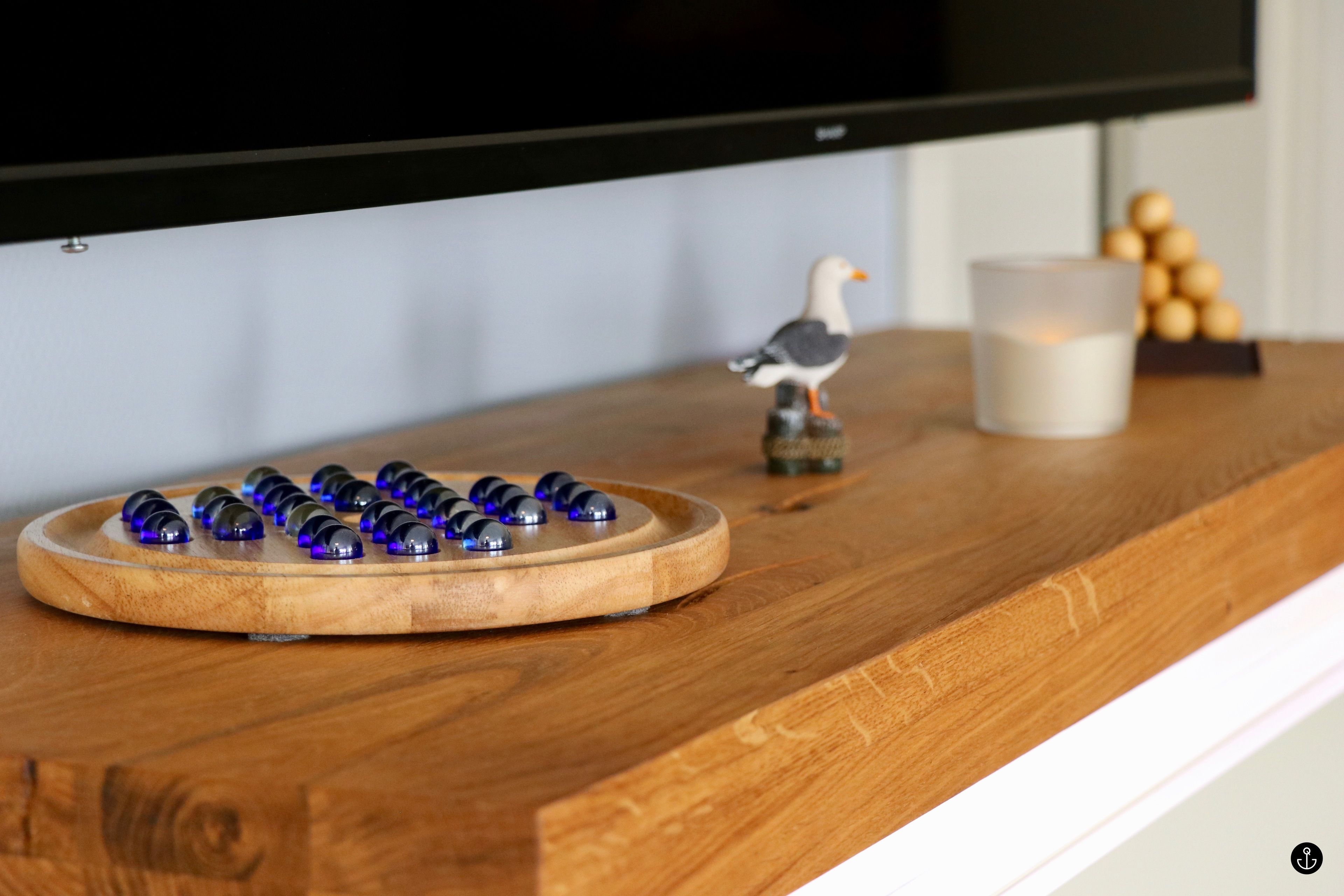 A wooden table with a board game, a figurine, and a candle.