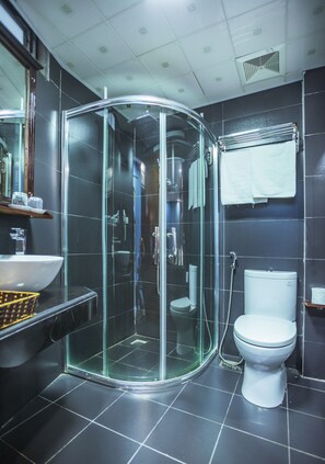 A modern bathroom with a glass-enclosed shower, a white toilet, and a sink with a black countertop. - Sapa Full House Hotel (Sa Pa)