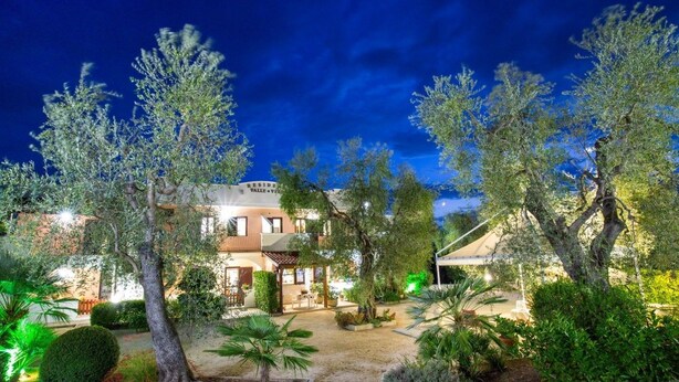 A villa with a covered outdoor seating area, surrounded by trees and well-lit pathways. - Residence Valleverde (Vieste)